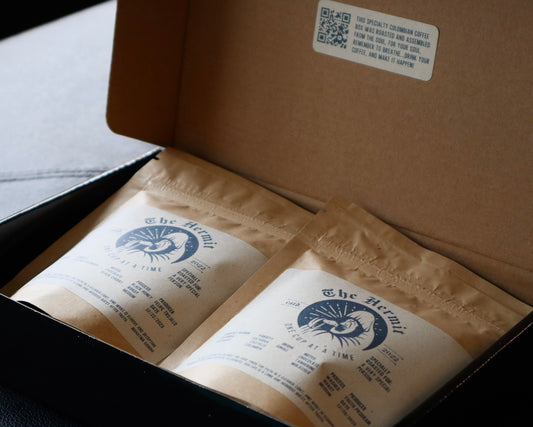 Black Hermit-branded box featuring specialty coffee and logo on wooden table