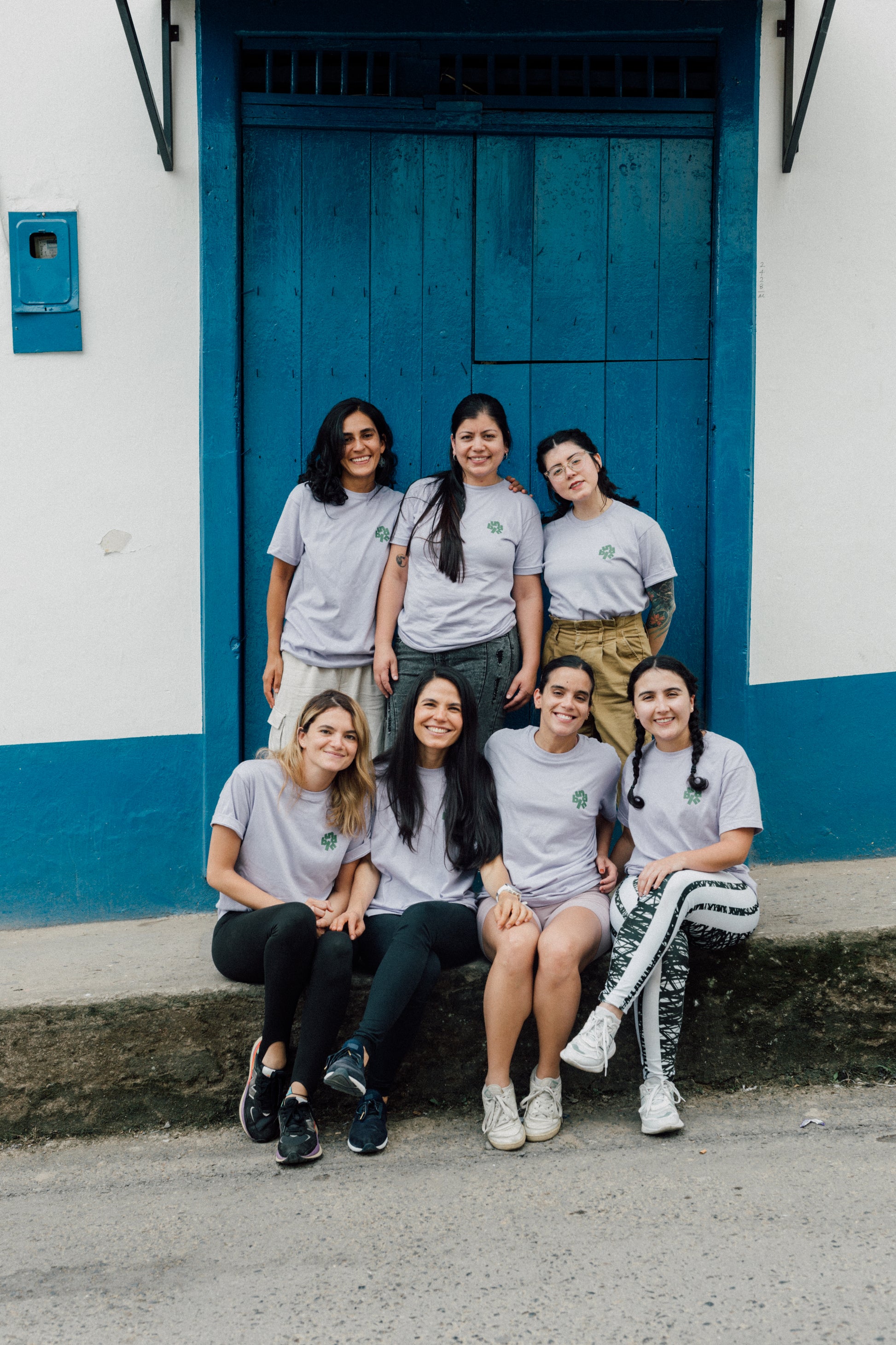 Group of women from unblended coffee posing in front of a blue door