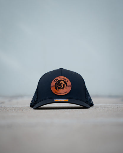 Black The Hermit Specialty Coffee cap with a brown logo on a light gray background